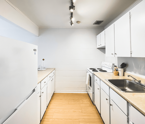 A kitchen with white cabinets and a white fridge.