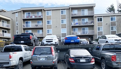 a parking lot full of cars in front of an apartment building