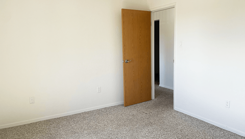 an open door in a room with a white wall and carpet