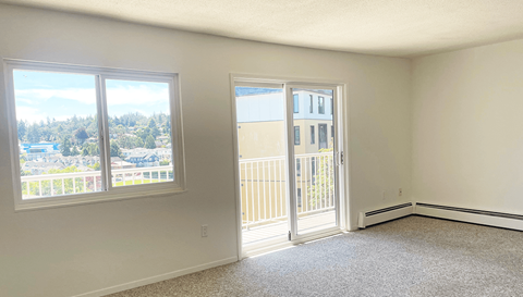 an empty living room with windows and a door to a balcony