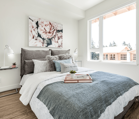 A bedroom with a large bed and a floral painting on the wall.
