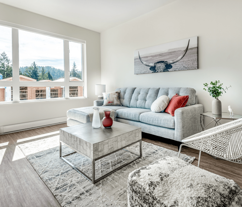 A living room with a grey sofa, a glass coffee table, and a white chair.