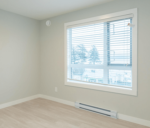 A room with a window showing a view of a residential area.