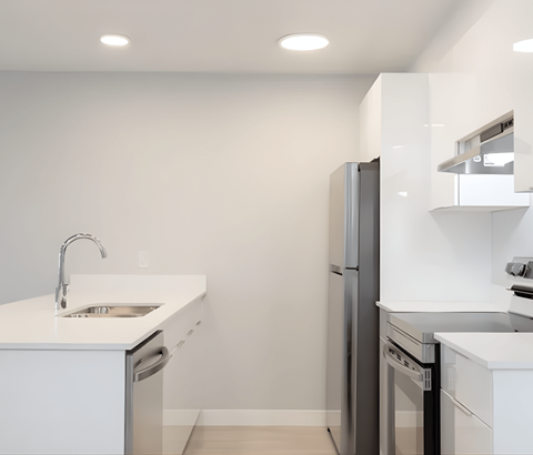 A modern kitchen with a white countertop and stainless steel appliances.