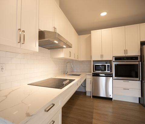 A kitchen with white cabinets and a marble countertop.