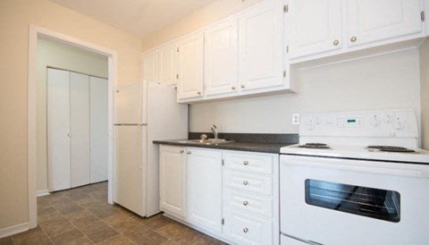 A kitchen with white cabinets and appliances.