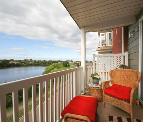 A balcony with a chair and a table with a view of a river.