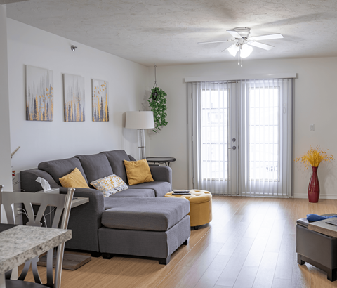 A living room with a grey couch and a yellow ottoman.