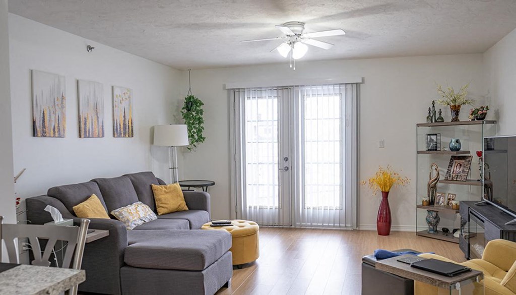 A living room with a grey couch and yellow ottoman.