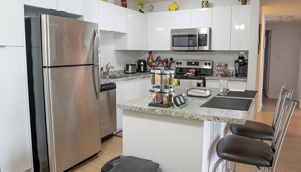 A kitchen with a refrigerator, microwave, oven, and sink.