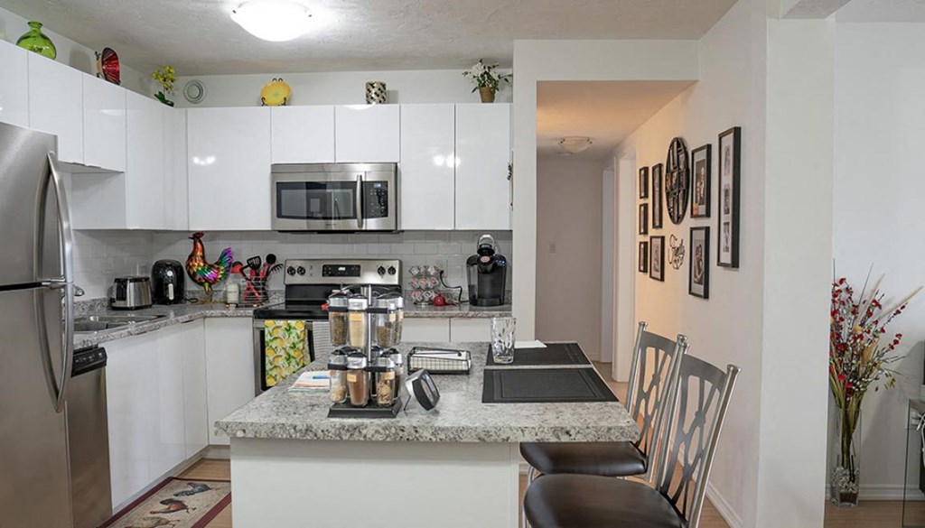 A kitchen with a refrigerator, microwave, oven, and sink.