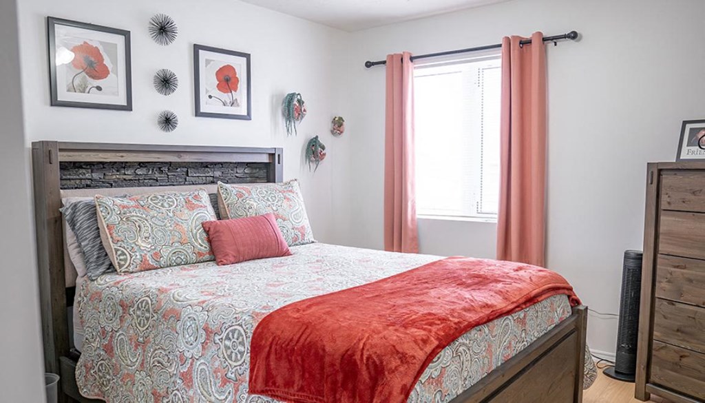 A bed with a red blanket and a wooden headboard.