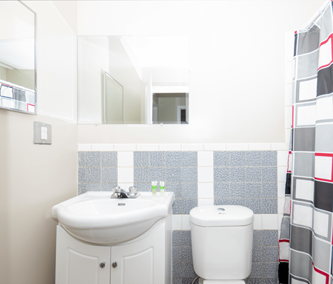 A white sink and toilet in a bathroom with a mirror above it.