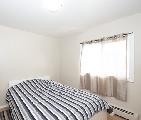 A bed with a striped comforter sits in a room with a window.