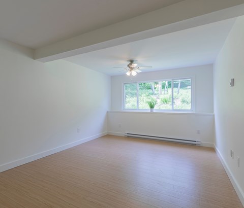 Empty room with a window and a ceiling fan.