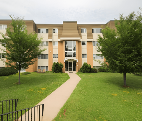 A building with a brown roof and tan walls with a walkway in front.