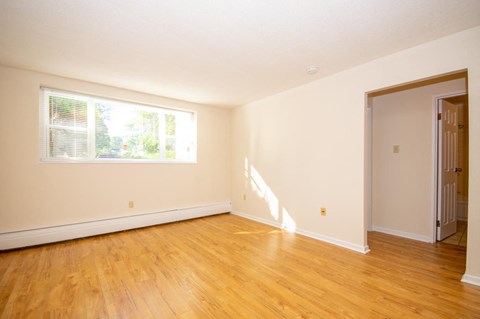 an empty room with a window and wooden floors
