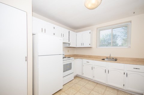 a kitchen with white cabinets and a sink and a refrigerator