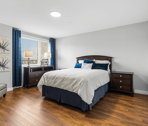 A bedroom with a large bed and a wooden floor.