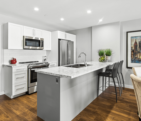 A modern kitchen with a marble countertop and stainless steel appliances.