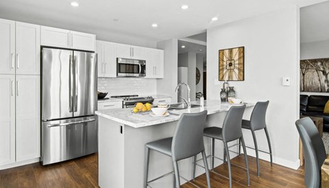 a kitchen with a marble counter top and stainless steel refrigerator