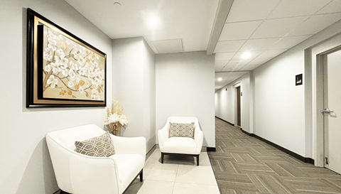 a hallway with white chairs and a large picture on the wall