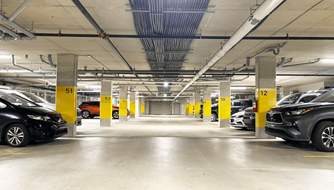 a parking garage with cars and yellow parking meters