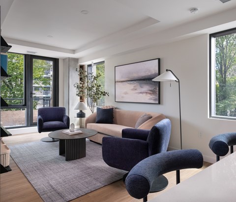 A living room with a grey rug and a large painting on the wall.