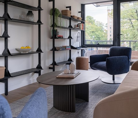 A living room with a round table, two chairs, and a bookshelf.