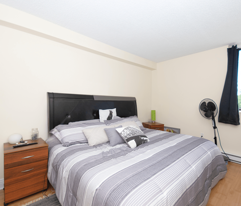 A bedroom with a bed, nightstand, and lamp.