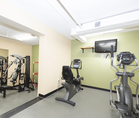A gym with a treadmill, exercise bike, and a television.