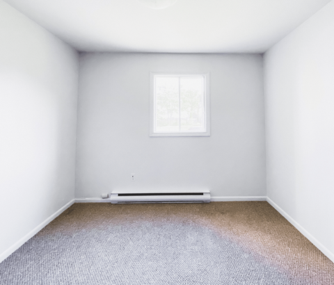 A room with a window and a radiator on the floor.