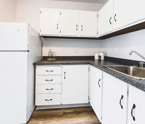 A kitchen with white cabinets and a black countertop.