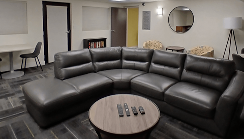 A black leather couch with a wooden coffee table in front of it.