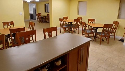 A dining room with a table surrounded by chairs.