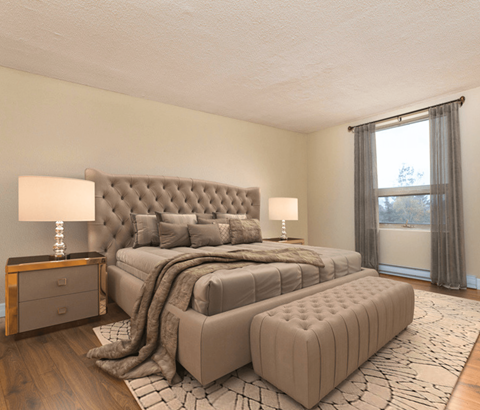 A bedroom with a large bed and a window with curtains.
