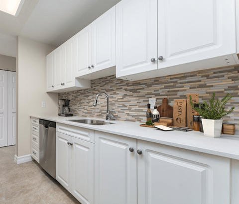A kitchen with white cabinets and a stone backsplash.