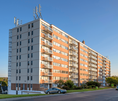 A large apartment building with a car parked in front.