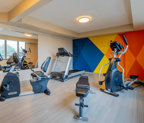 A gym with a row of exercise bikes and elliptical machines.