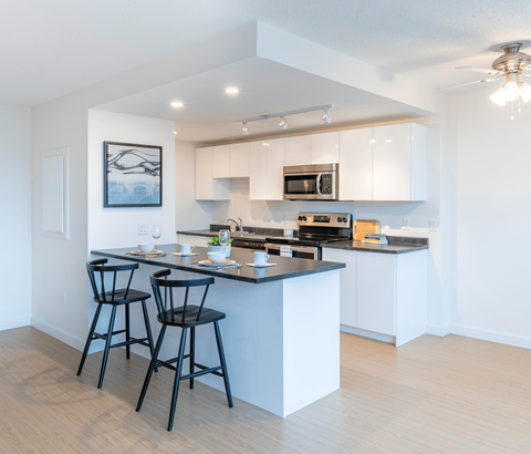 A kitchen with a bar area and two black chairs.