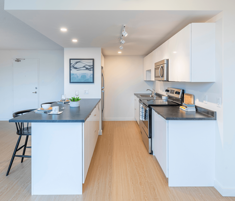 A kitchen with white cabinets and a black countertop.