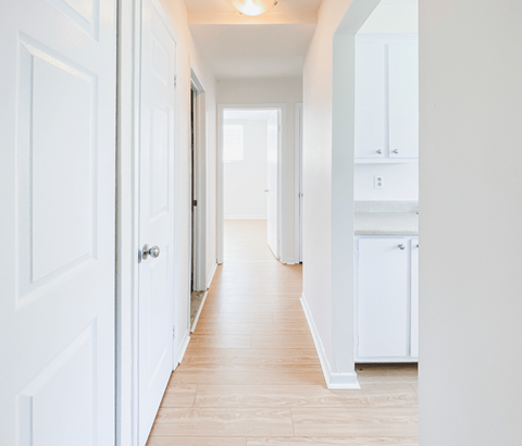 A long hallway with white doors and cabinets.
