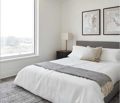 A bedroom with a large bed and two pictures on the wall.