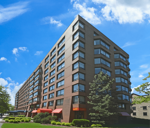 A tall building with many windows and red awnings on the lower level.