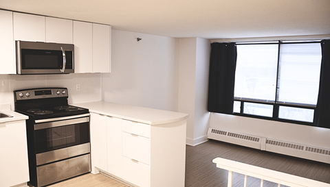 A kitchen with white cabinets and black appliances.