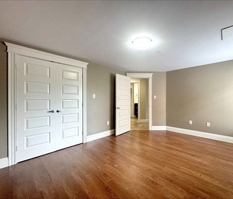 A room with a white door and wooden flooring.