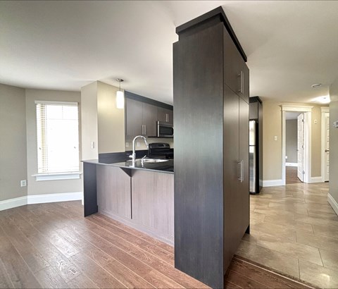 A kitchen with dark wood cabinets and a black countertop.