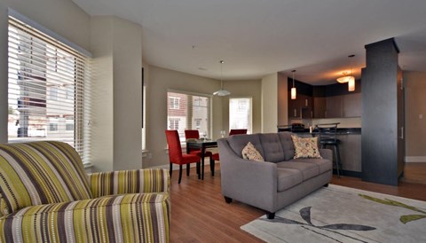 A living room with a striped chair and a grey couch.