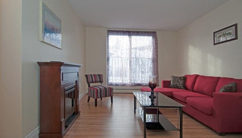 A living room with a red couch and a wooden cabinet.