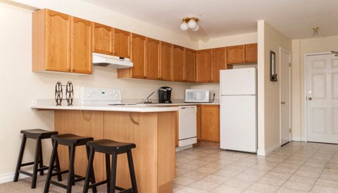 a kitchen with wooden cabinets and a counter with three stools